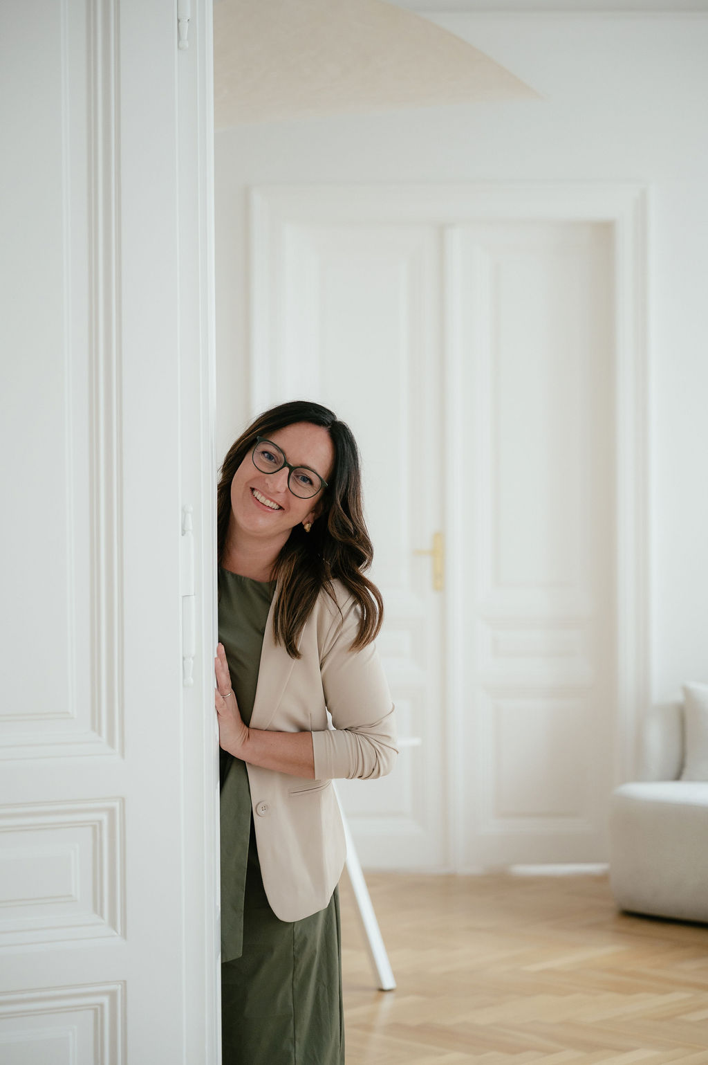 Daniela Reisner in einem Altbauraum; blickt hinter eine weißen Altbautür hervor.