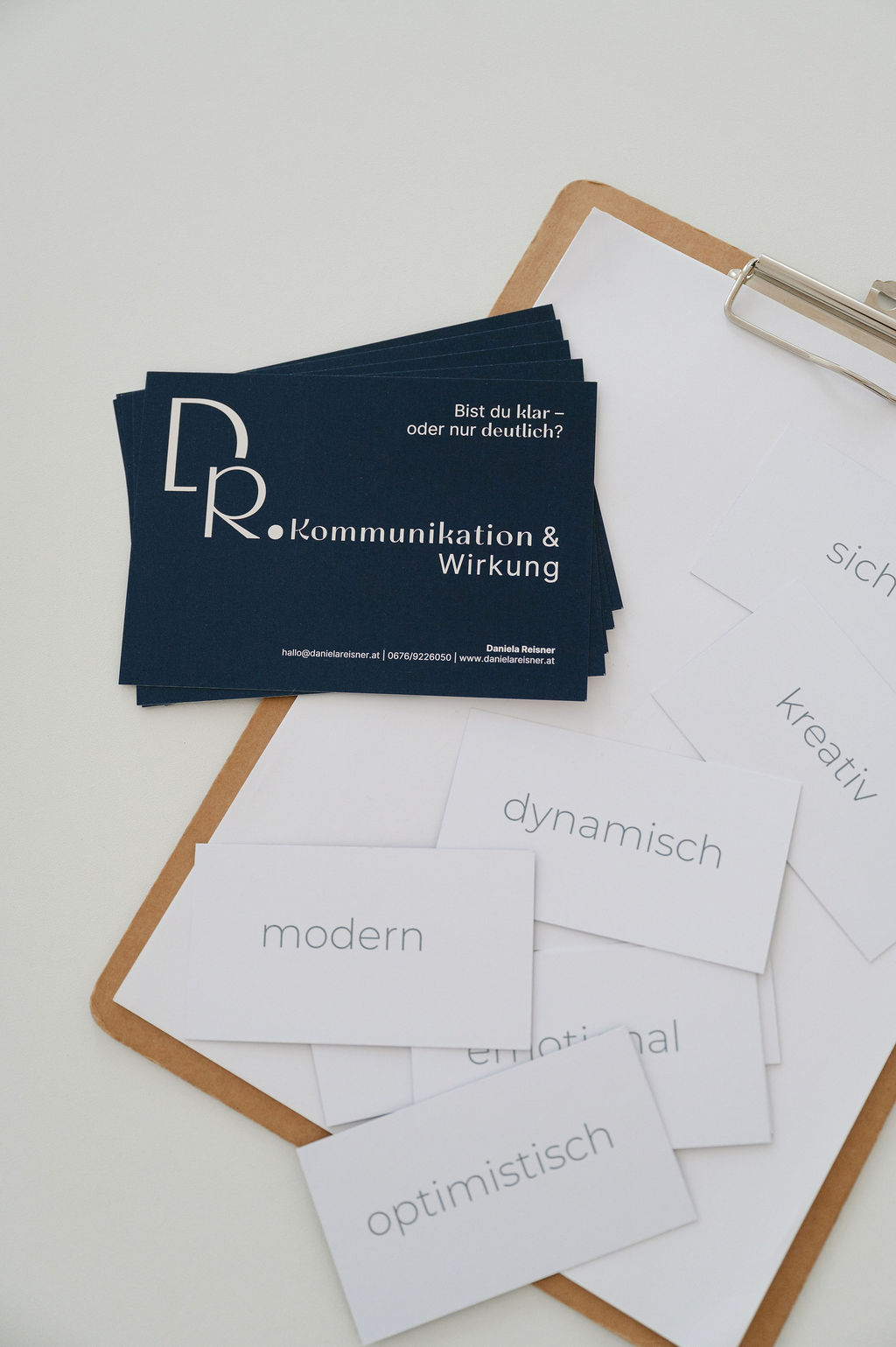 Infokarten mit der Botschaft von Daniela Reisner, Kommunikation und Wirkung in dunkelblau, rundherum Werte-Karten und ein Klemmbrett
