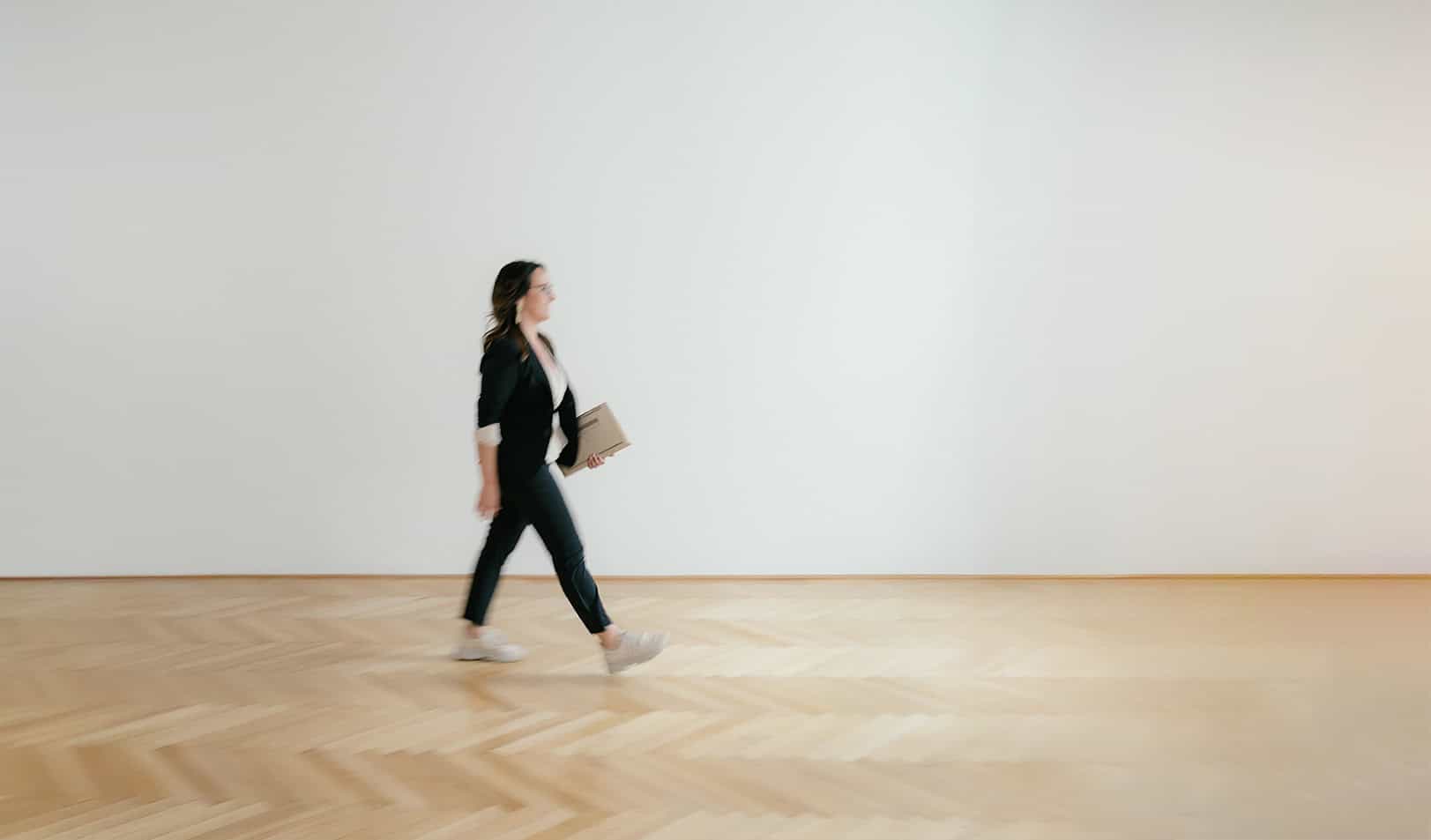 Daniela Reisner, Coach für Klarheit und Wirkung spaziert mit Elan und Laptop in der Hand vorwärts.